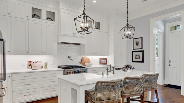 A kitchen with white cabinetry, a central island with bar stools, a stove, and pendant lighting. - Heated Pool Access | 5*Clean | Flex Cancelation (Savannah)