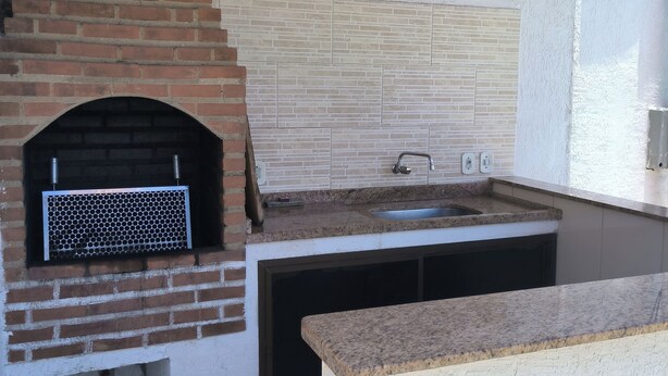 Cocina exterior con horno de ladrillo, pileta y salpicadero azulejado.