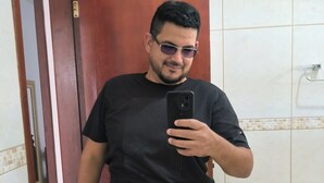 Un hombre tomándose un selfie en un baño con un espejo, un lavabo y una puerta.