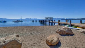 Una spiaggia con barche, un molo di legno e grandi rocce.