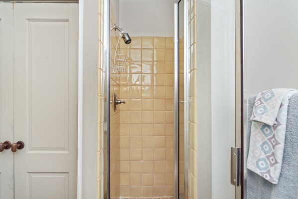 Une salle de bain avec une douche à parois de verre, une porte blanche et un porte-serviettes orné d’une serviette à motifs.