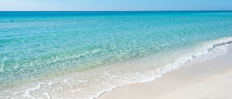 A beach with clear turquoise water and white sand.
