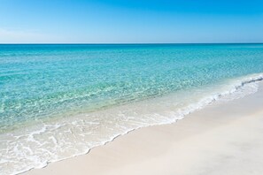 Ein Strand mit klarem türkisblauem Wasser und weißem Sand.