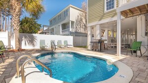 A swimming pool with a metal ladder, surrounded by patio furniture and a covered outdoor area with tables and chairs. - Surfside Beach 5 Bdr, Walk 2 Beach, Priv Pool, Putt Green, Golf Cart (Surfside beach)