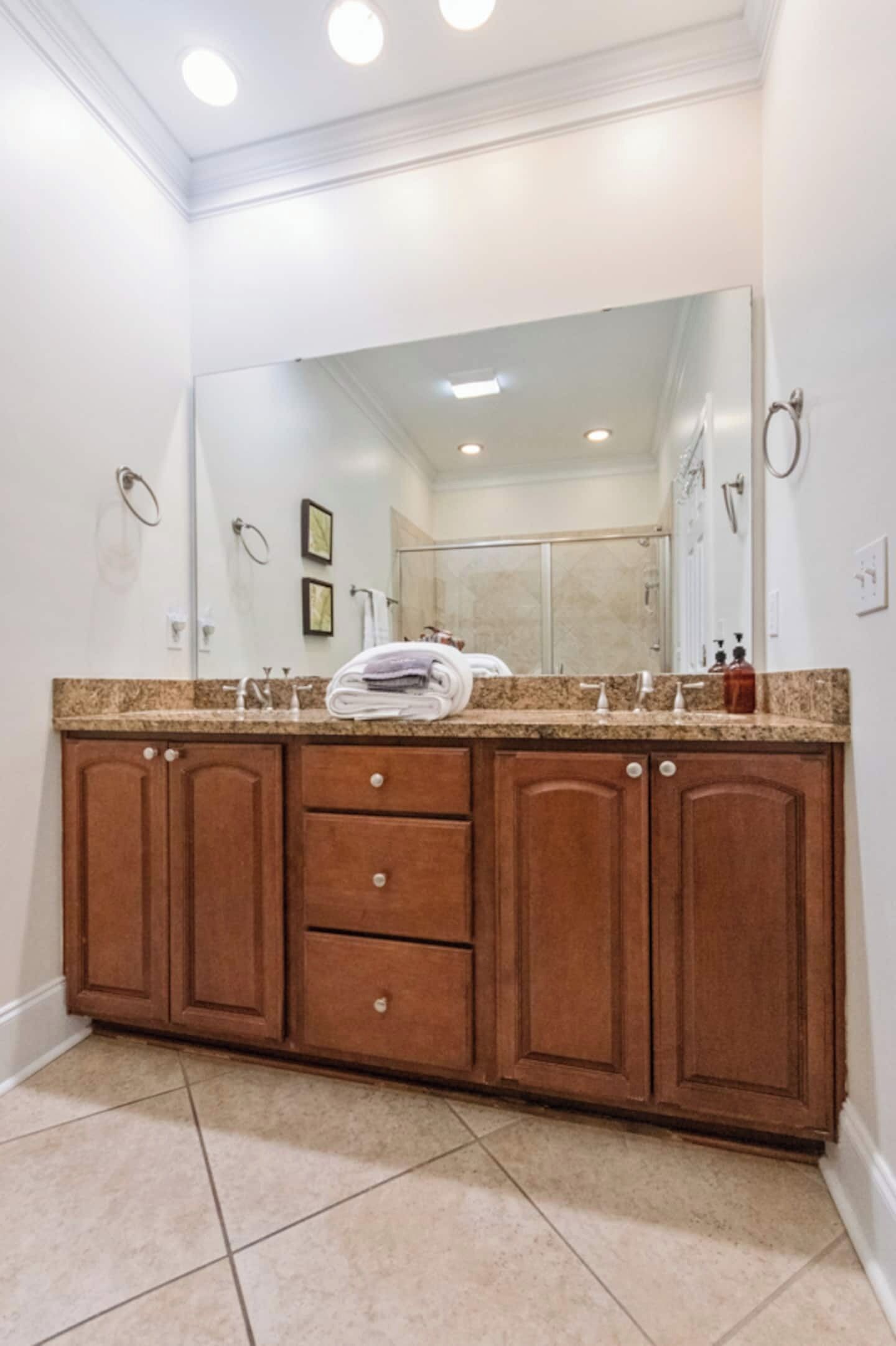 A bathroom with a large mirror, a double sink vanity, and a towel rack.
