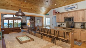 Amplia sala de estar con techo de madera, una gran mesa de comedor y cocina con armarios de madera y electrodomésticos modernos.