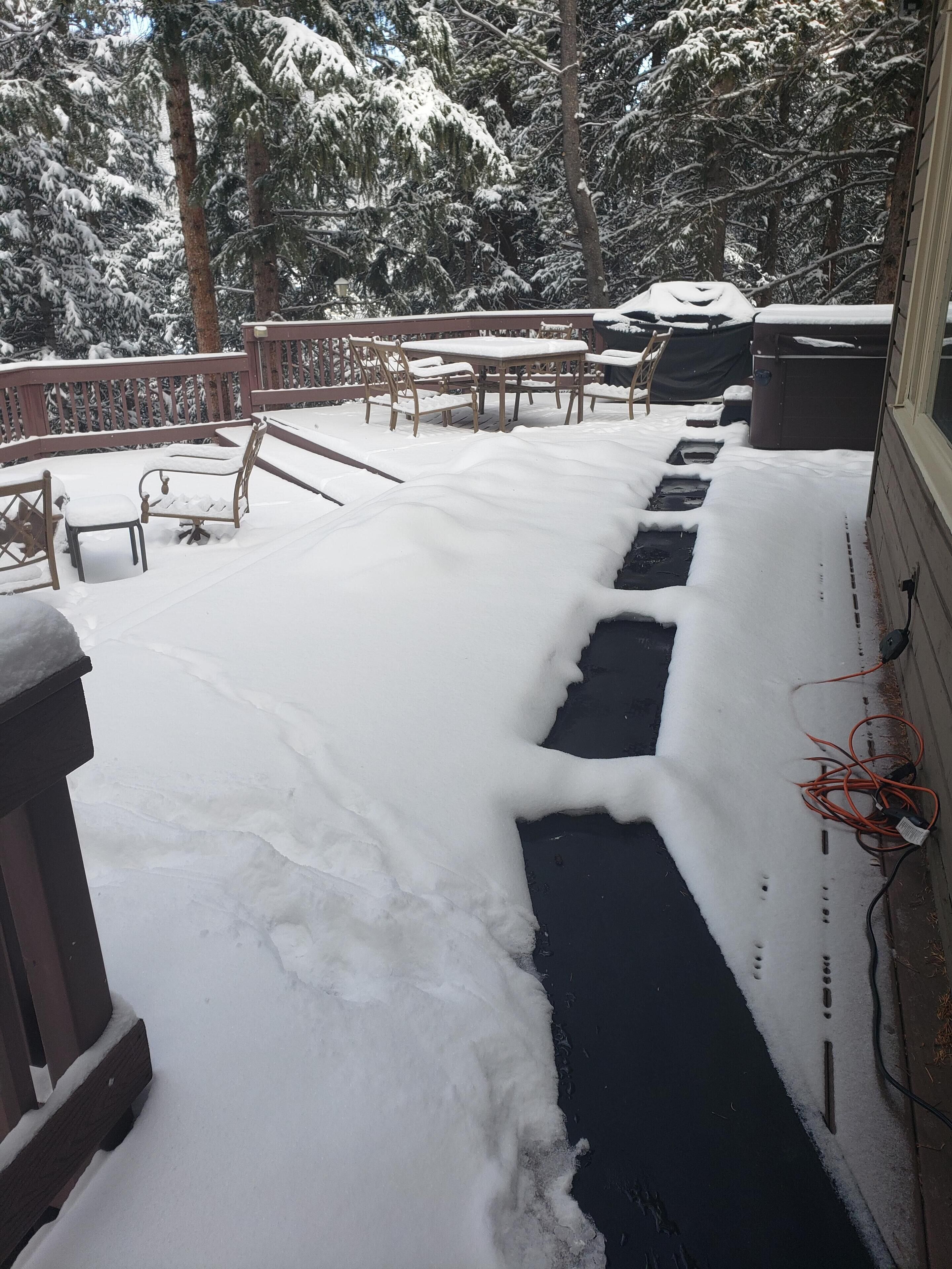 Un patio cubierto de nieve con muebles de exterior y barandilla de madera.