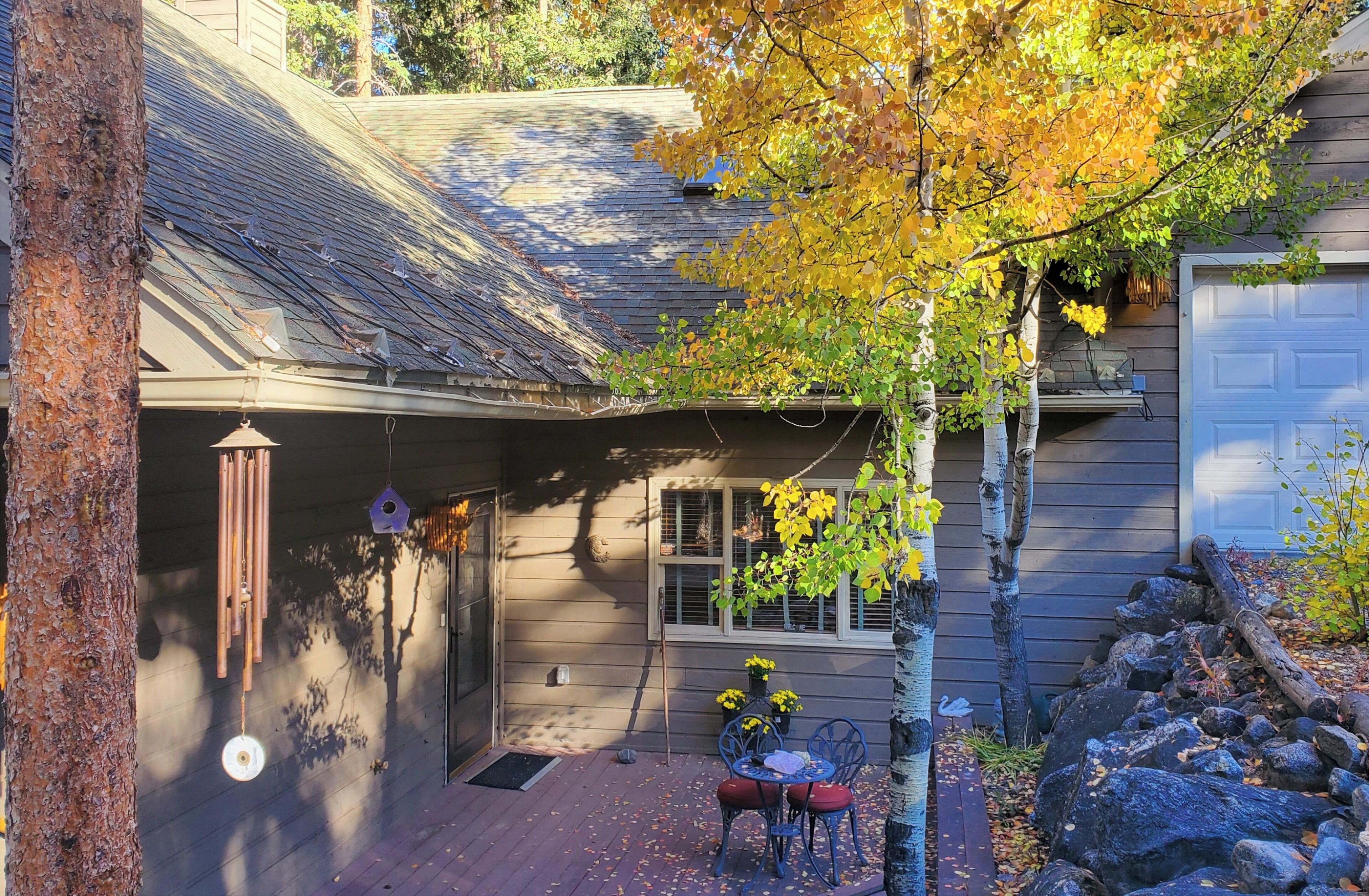 A house with a covered porch, a bird feeder, and a small table with chairs.