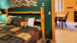Un dormitorio con estructura de cama de madera, colcha acolchada y una obra de arte con motivos de montaña en la pared.
