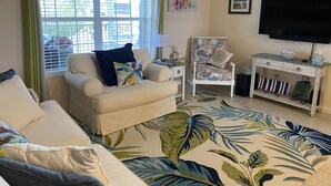 A living room with a sofa, armchair, and a TV mounted on the wall. - Nader Vacation Rental (Little Torch Key)