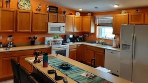 A kitchen with wooden cabinets, a microwave, a stove, and a refrigerator. - Nader Vacation Rental (Little Torch Key)