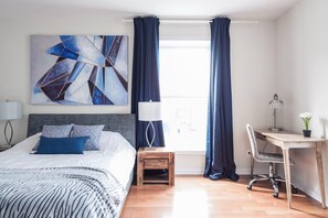 Una habitación de hotel moderna con una cama grande, un escritorio y vistas a la ciudad.