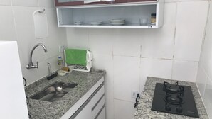 Ett kompakt kök med en bänkskiva i granit, en diskho i rostfritt stål, en inbyggd mikrovågsugn och en gasspis.