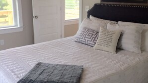 A bedroom with a bed, a door, and a window.