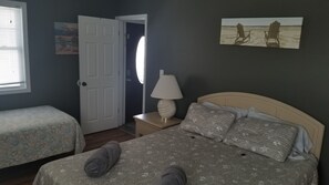 A bedroom with two beds, a nightstand, a lamp, and a painting on the wall.
