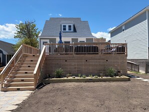 Ein Wohnhaus mit einer Holzterrasse, einer Treppe und einem eingezäunten Garten.