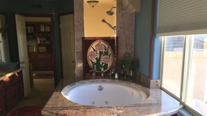 A bathroom with a freestanding bathtub, a vanity with a mirror, and a window with blinds.