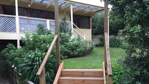 A wooden staircase leading to a covered outdoor area with a view of a garden and a house in the background. - The Shelter bnb @ Robe SA (Robe)