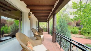 Un espacio exterior techado con mobiliario de mimbre y vistas al jardín.