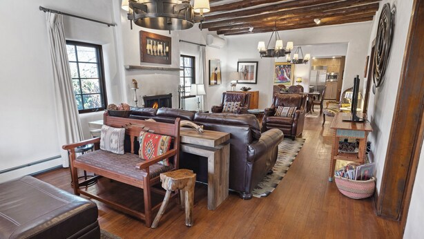 Amplia sala de estar con chimenea, sofás de cuero, muebles de madera y techo rústico.
