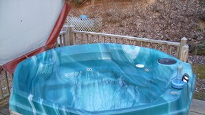 Un jacuzzi con terraza de madera y una valla de madera al fondo.