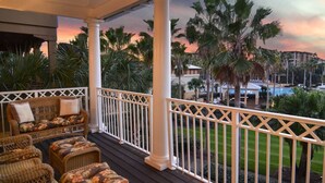 A covered outdoor area with wicker furniture and a view of a pool and palm trees. - Seacrest 4BR Escape with Resort Views + Bikes (Inlet Beach)