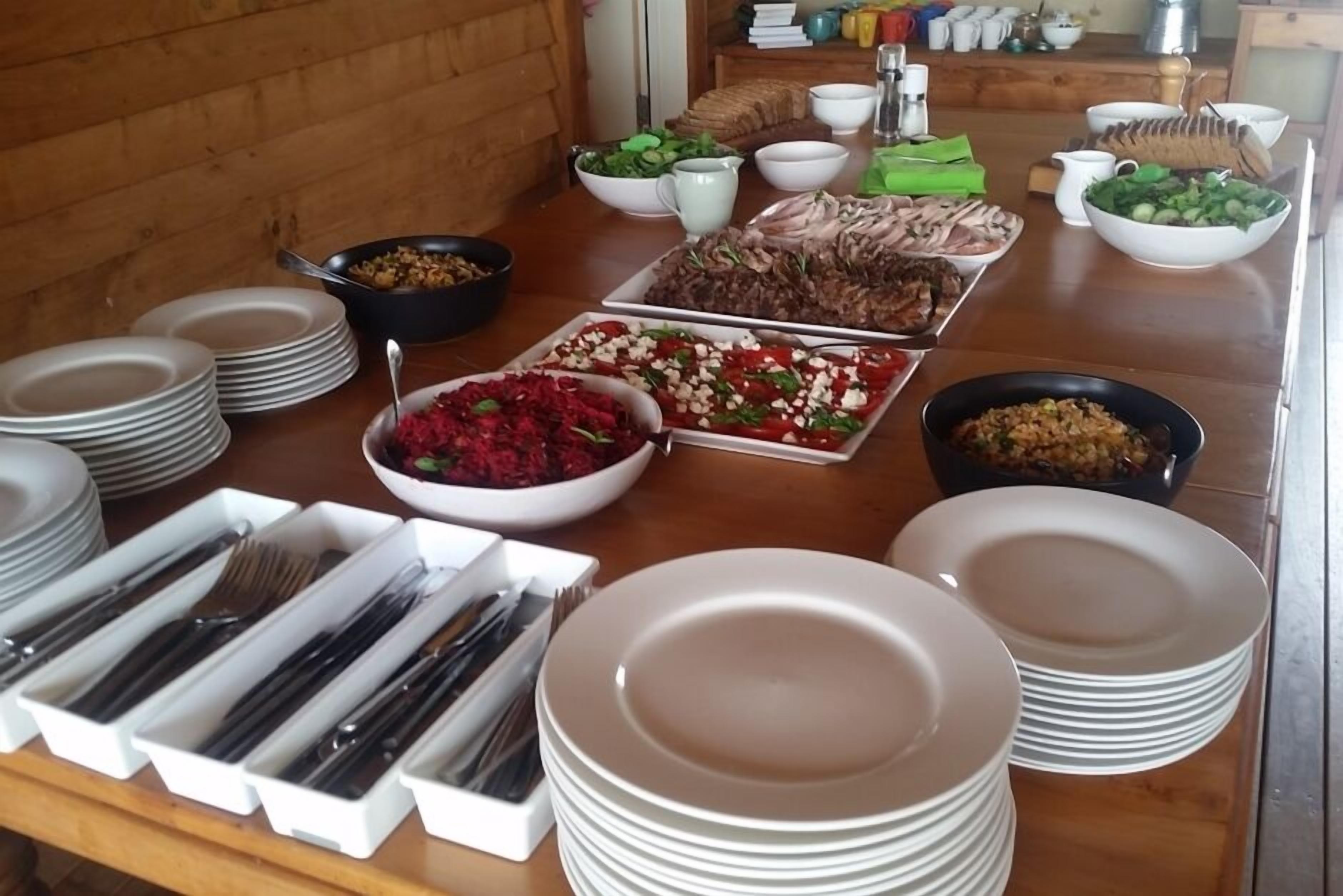 Une table de buffet proposant divers plats, avec une présentation soignée des assiettes et des couverts.