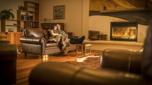 Una sala de estar acogedora con un sofá de cuero, una chimenea, estanterías de madera y una biblioteca.