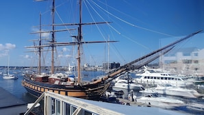 Un barco histórico de vela atracado en un puerto deportivo junto a otras embarcaciones, rodeado de edificios.