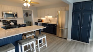 Una cocina moderna con una isla central, electrodomésticos de acero inoxidable y armarios azul oscuro.