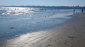 Una playa con gente caminando por la orilla y el océano al fondo.