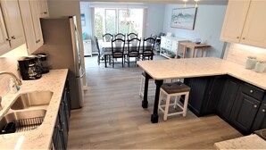 Una cocina moderna con una isla central, un área de comedor con sillas y vistas al exterior.