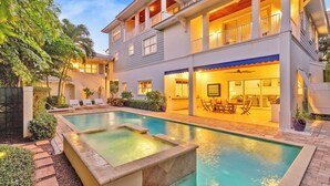 A two-story house with a swimming pool, outdoor seating, and a covered patio area. - Luxury Beach Retreat - 200 Steps to Beach - Heated Pool, Spa & Elevator (Jupiter)