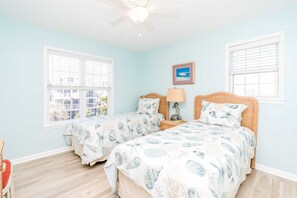 A bedroom with two beds, a ceiling fan, and a window with blinds. - Sundog - Spacious 4 BR Oceanfront Home with 2 Sun Decks (North Topsail Beach)