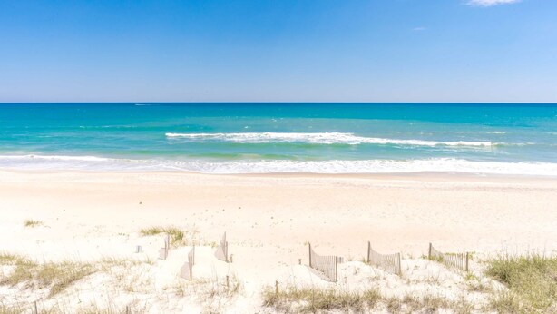 Ein Strand mit einer Holzumzäunung und Dünen.