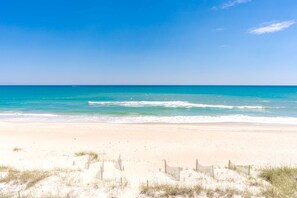 A beach with a wooden fence and sand dunes.