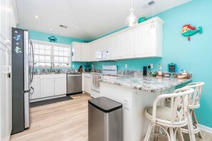 A kitchen with white cabinets, a stainless steel refrigerator, a microwave, and a sink. - Sundog - Spacious 4 BR Oceanfront Home with 2 Sun Decks (North Topsail Beach)