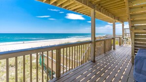 Eine Holzterrasse mit Blick auf Strand und Meer.