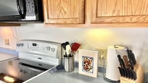 A kitchen with a stove, microwave, and wooden cabinets. - Quiet oasis across the street from Acadia and just steps from the harbor (Seal Harbor)