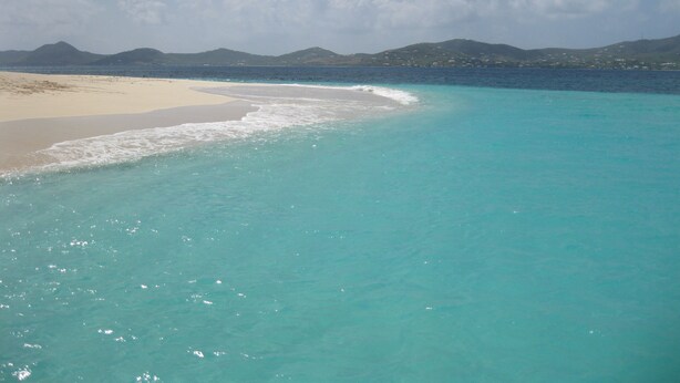 Ein Strand mit klarem türkisblauem Wasser und einem sandigen Ufer.