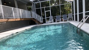 A clear indoor swimming pool with a wooden deck, metal railings, and lounge chairs. - Key West Style Florida Charm w Heated Private Salt Pool, close walk to Beach (Marco Island)