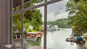 Une vue sur un lac où sont amarrés des bateaux, avec une petite maison et un bâtiment plus grand de l’autre côté.