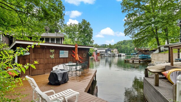 Une jetée avec une table et des chaises, un espace abrité et une vue sur un lac où se trouvent des bateaux.