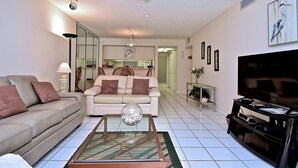 Una sala de estar con sofá, mesa de centro, televisor y ventilador de techo.