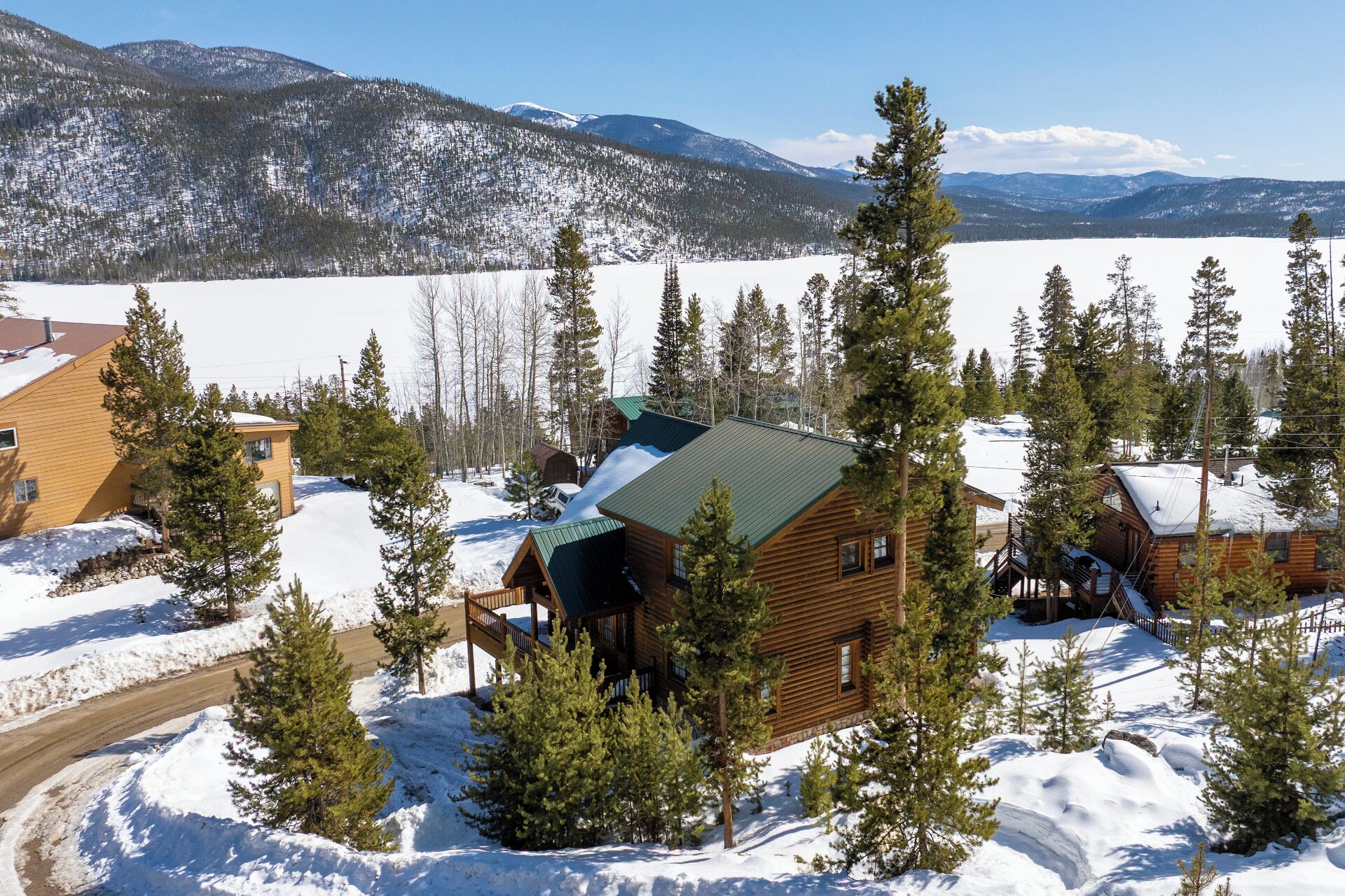 A log cabin surrounded by snow-covered landscape and pine trees.