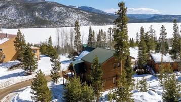 A log cabin surrounded by snow-covered landscape and pine trees.