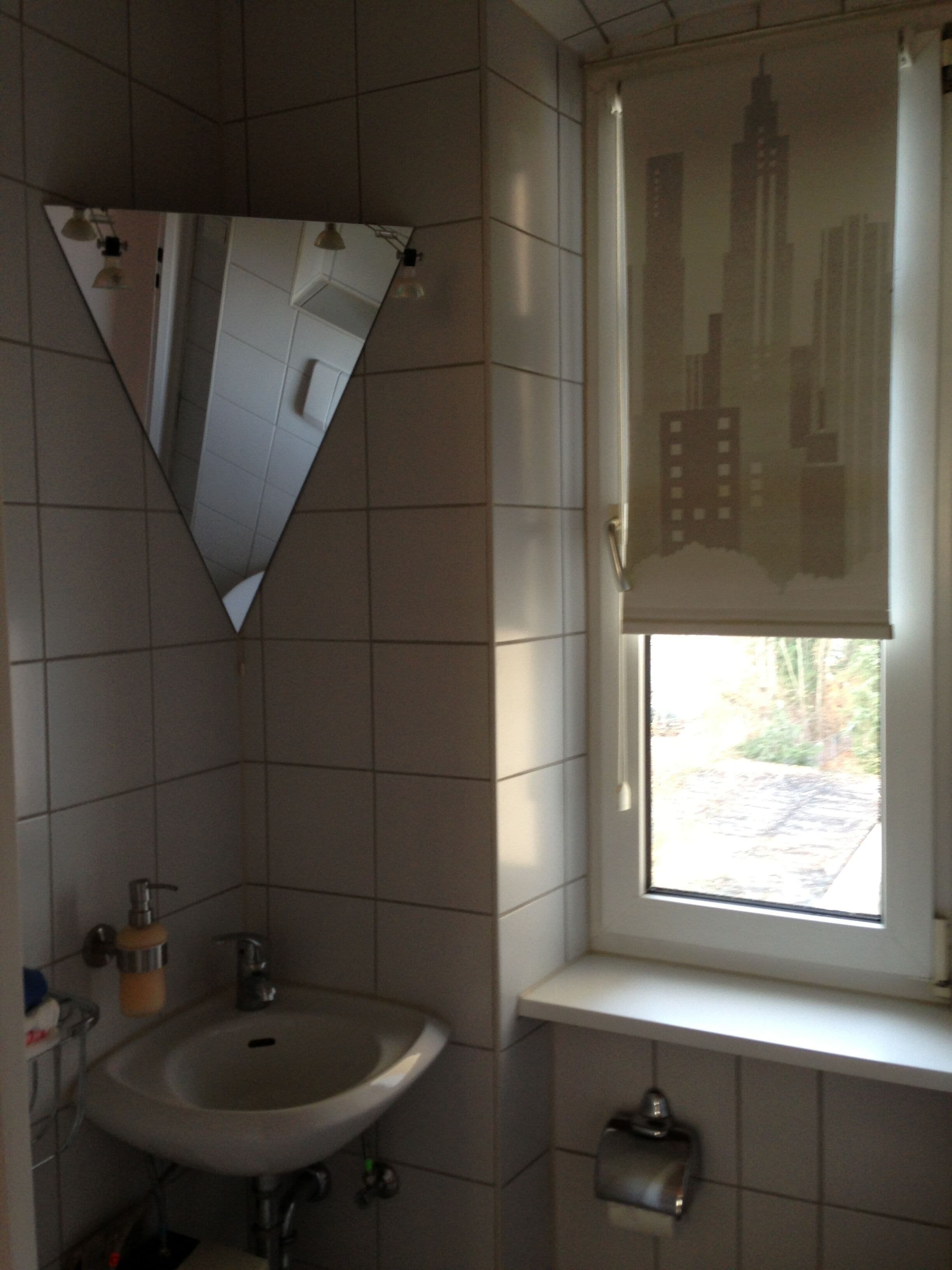 A bathroom with a sink, mirror, and window with a cityscape view.