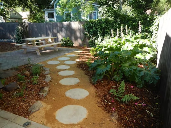 A garden path with stepping stones, a wooden bench, and a fence.