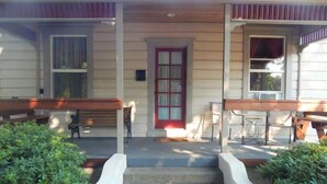 Una vista frontale di una casa con portico, una porta rossa e una scalinata che conduce all'ingresso.