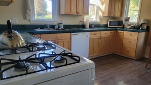Una cucina con piano cottura a gas, mobili in legno, lavastoviglie e forno a microonde.